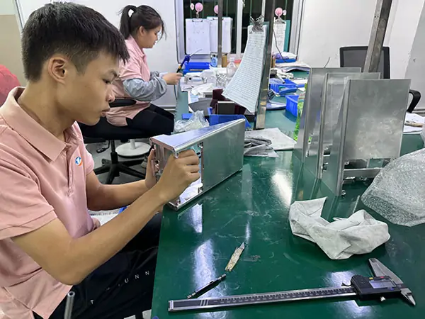 Operator performing CNC quality check using caliper to measure machined aluminum parts
